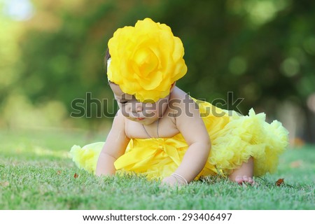 Little asian girl wearing a yellow dress was playing happily in the park, close up