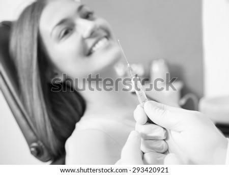 dentist hand holding a syringe, making a numb shot for woman patient