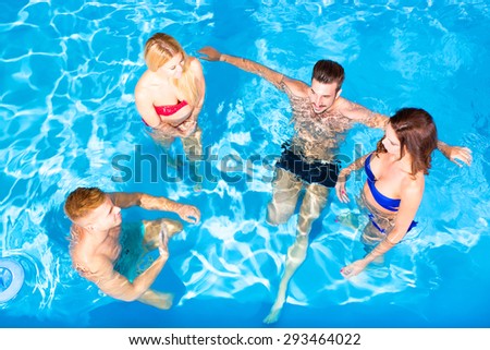 A group of young friends having fun in a swimming pool. 