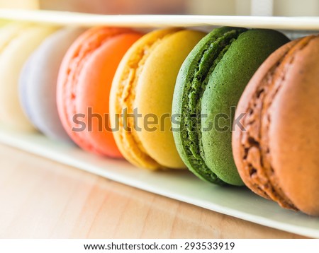 Sweet green  french macarons or macaroons between  colorful macarons  in row of box, near a window with sunlight.