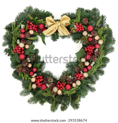 Christmas heart shaped wreath with baubles, gold ribbon bow, holly, mistletoe and winter greenery over white background.