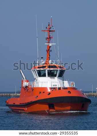 A huge orange tugboat in a harbor