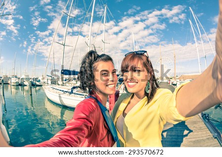 Young women girlfriends taking selfie with sailboats - Friendship concept with new trends and technology - Best female friends catching the moment with modern smartphone - Soft vintage filtered look
