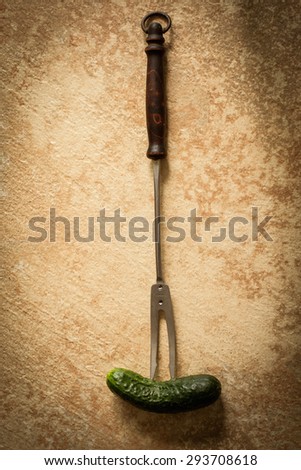 Old vintage fork for meat and green cucumber