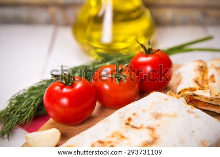tortilla,tomatoes,dill,garlic and oil in bottle on wooden plate in studio