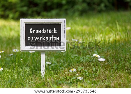Sign in the grass with "property for sale" in german language