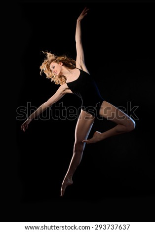 Slim ballet dancer in motion on black studio background