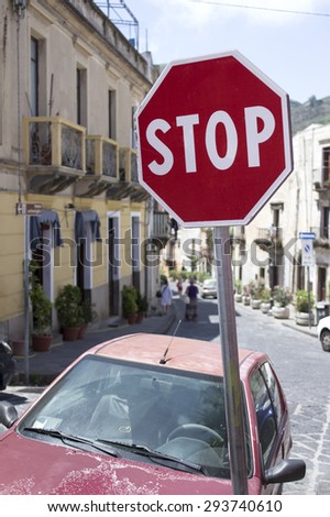 Tilted Stop Sign in focus, blurred street with people walking in the background