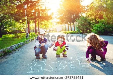 Happy children is drawing on asphalt in spring park. Background toning for instagram filter.