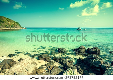 Dramatic photo of beautiful tropical beach- Tourist boat near rocky beach. Cross processed