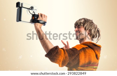 Blonde man filming over ocher background