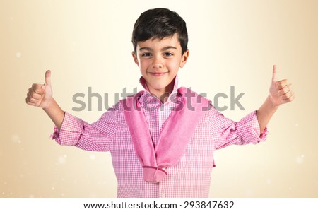 Boy with thumb up over ocher background 