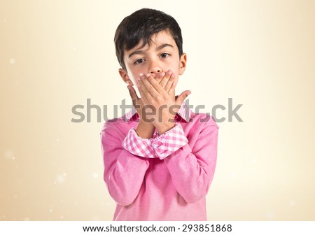 Kid covering his mouth over ocher background