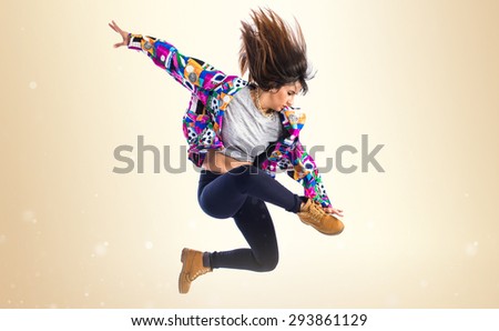 Girl jumping in hip hop style over ocher background