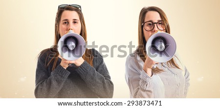 Twin sisters shouting over ocher background