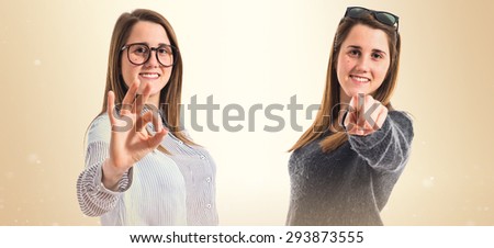 Twin sisters pointing to the front and doing OK gesture