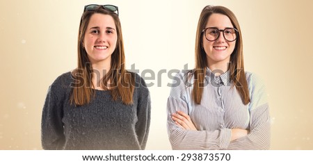 Twin sisters with their arms crossed over ocher background