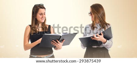 Twin sisters holding books over ocher background  