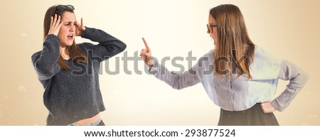 Girl shouting at her sister over ocher background  