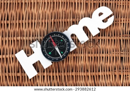 White Wood Sign Home  And Modern Magnetic Travel Compass On The Rustic Wicker Background