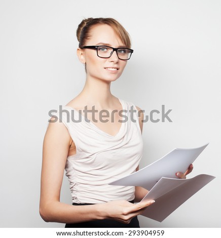 Business, finance and people concept:  young  business woman hold pages of paper. Paperworker. Over grey background.
