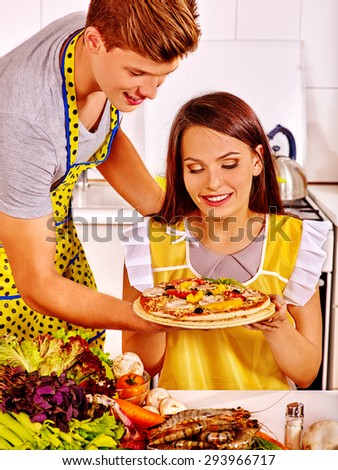 Young happy couple cooking pizza at kitchen. Woman looking on food.