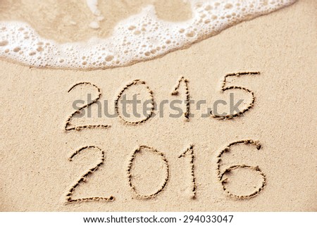 2015 2016 inscription written in the wet yellow beach sand being washed with sea water wave. Concept of celebrating the New Year at some exotic place