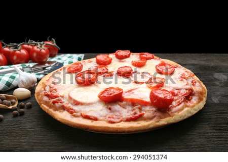 Delicious pizza with cheese and cherry tomatoes on wooden table on dark background