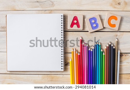 Colorful alphabet letters "abc" ,crayons and the note book on wooden background