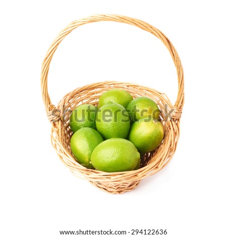 Wicker basket full of multiple ripe green limes, composition isolated over the white background