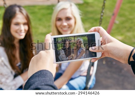 happy memories of girl friends being captured by mobile cell phone camera outdoors