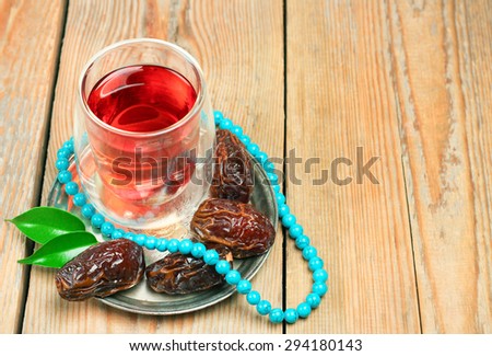 Still life, food and drink, holidays concept. Ramadan dates, tea and beads on a wooden table. Selective focus, copy space background