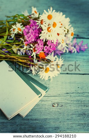 Vintage books with bouquet of daisy flowers/ nostalgic summer background