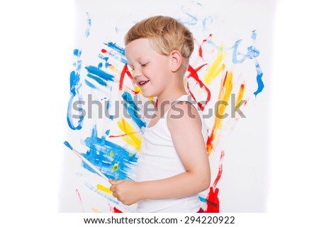 Little kid painting paints picture on easel. Education. Creativity. Studio portrait over white background