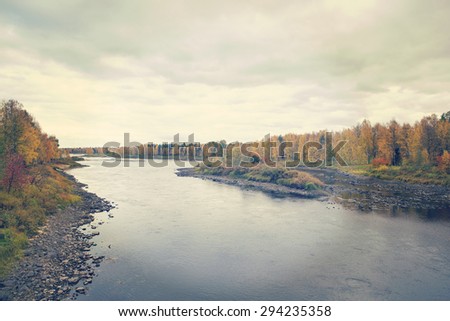 A beautiful river scene in northern part of Finland. Image taken during autumn. Image also has a vintage effect.