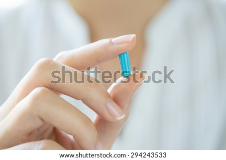 Closeup shot of a woman showing blue capsule pill. Female hand holding a medicine. Shallow depth of field with focus on blue capsule pill.
 Royalty-Free Stock Photo #294243533