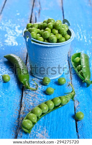 Fresh green peas in a drop of water on a wooden surface