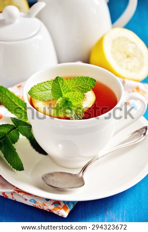 Tea with lemon and mint on a blue background. Table setting for tea time. Selective focus