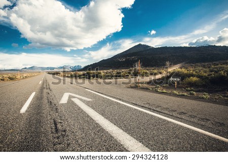 Wide angle picture of driving on an empty road through the beautiful landscape at sunny day. Concept vision for a new beginning with a sign start and an arrow towards the sun.