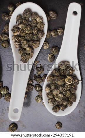 Green tea pearls in japanese white spoons on the black metal tray