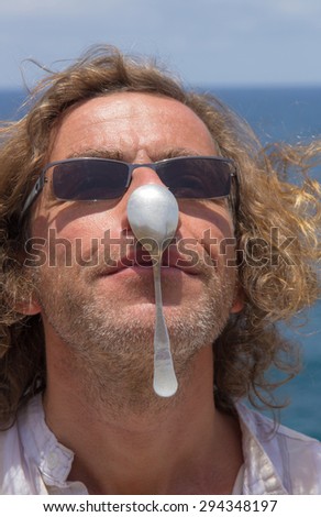Man trying to balance a spoon on his nose