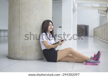 young attractive asian  girl in a uniform of university student Who using a tablet computer