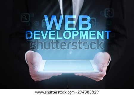 Businessman holding a tablet pc with "web development" text on virtual screen. Internet concept. development. 