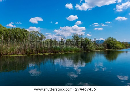 Landscape photo of a river and bright blue sky above.
