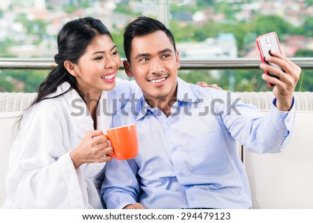 Asian couple taking selfie picture on balcony