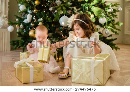 two little girl in Christmas with presents on floor