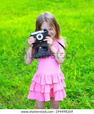 Summer portrait child with old retro vintage camera having fun outdoors on the grass