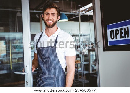 Smiling worker putting up open sign at the bakery