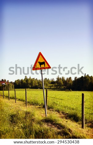 A warning sign on side of the road. This warning sign is for cattle. Image has a vintage effect applied. 