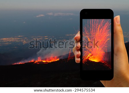 Tourist photographing the volcano eruption on smartphones  